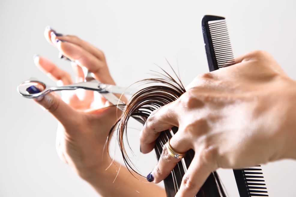 Hand with a comb cutting hair of woman